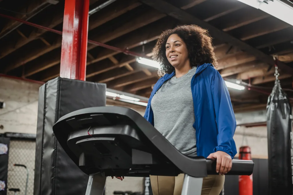 woman smiling while standing on treadmill cardiovascular