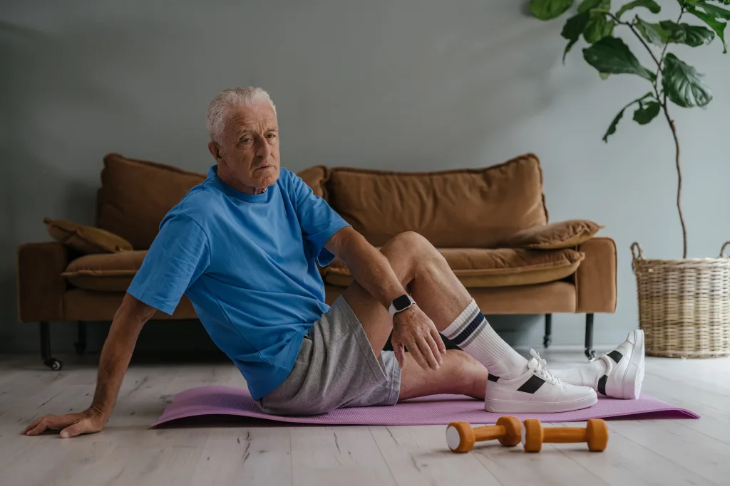 elderly man sitting on yoga mat beside dumbbells fasting