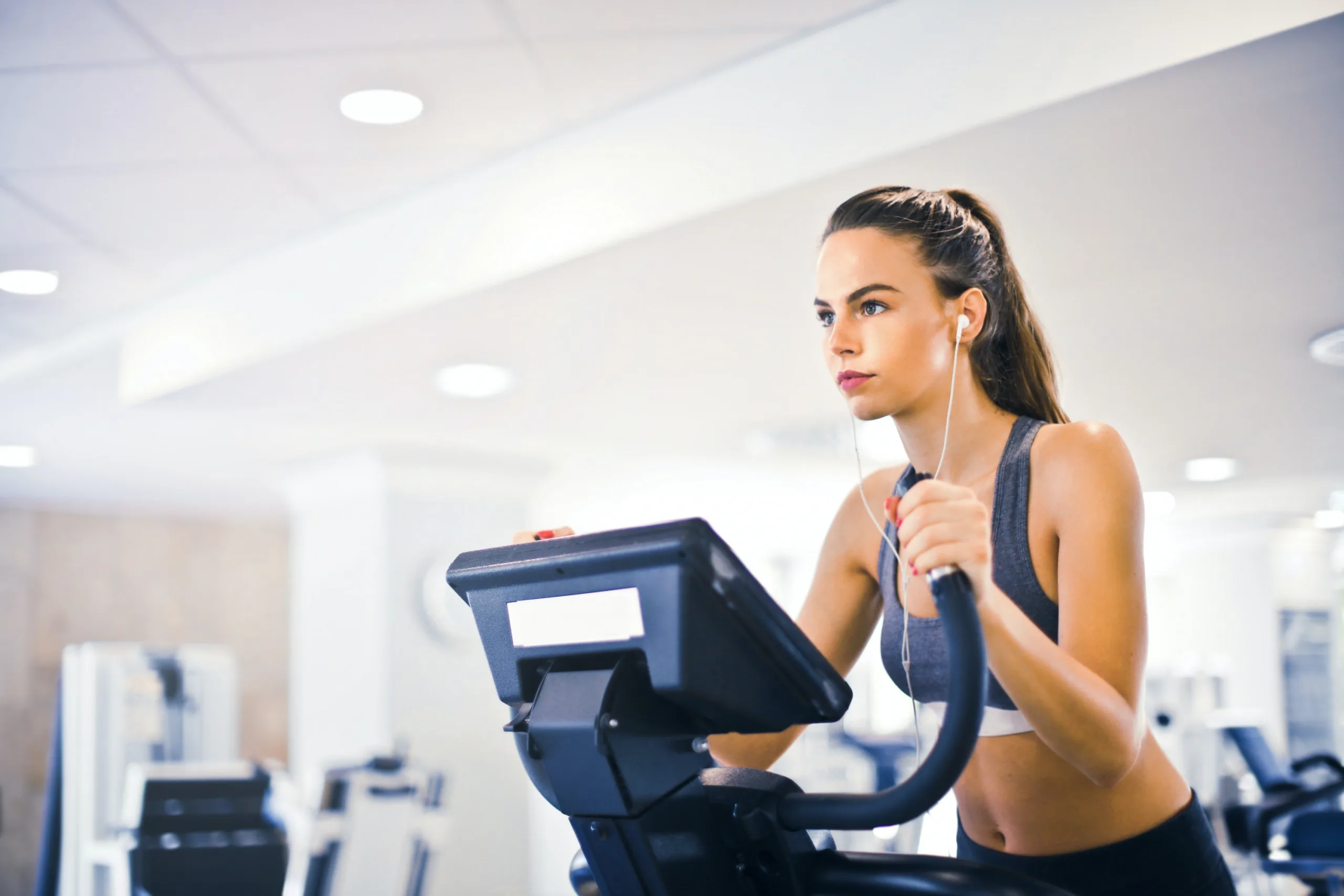 focused woman exercising in treadmill while listening to music