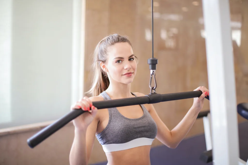 fit woman wearing gray tank tops doing pull ropes workout in the gym for weight loss
