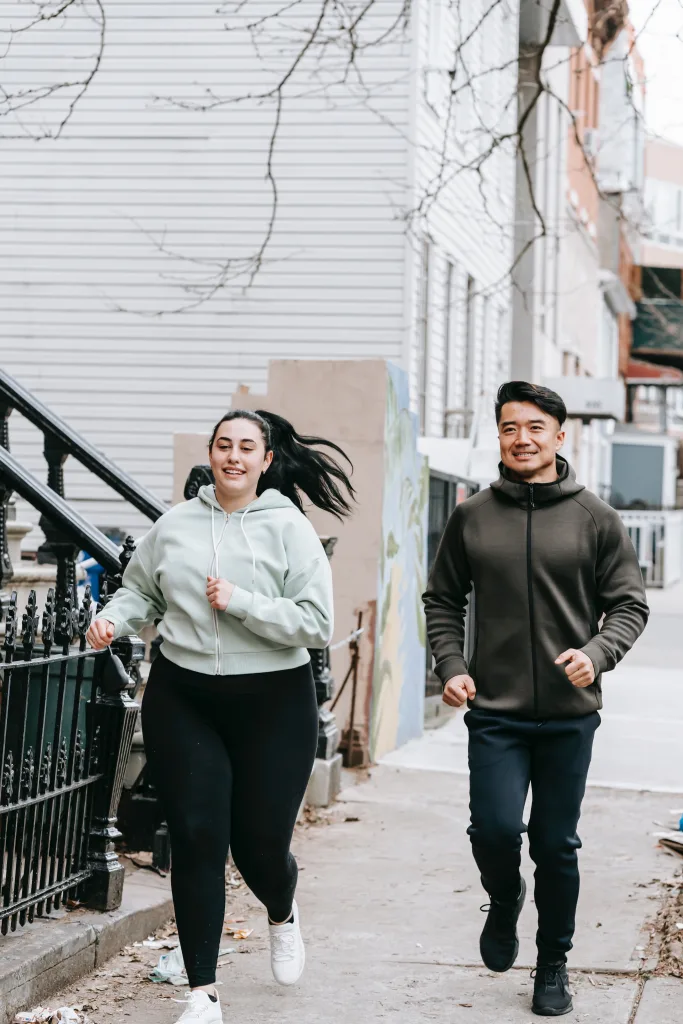 Man and woman smiling while running on the pavement