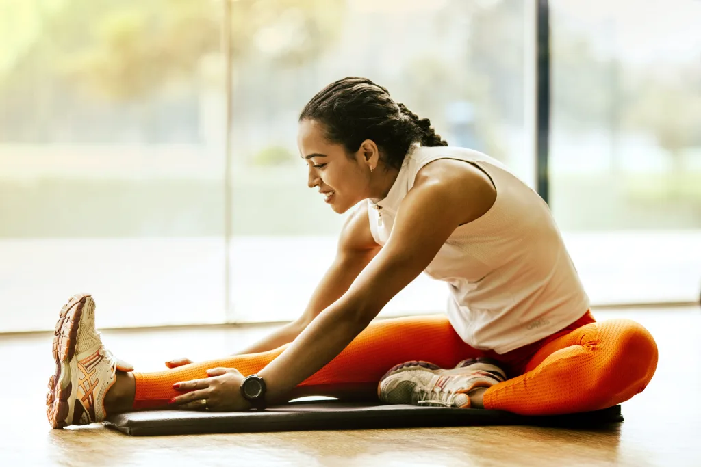 happy woman sitting on yoga mat reaching her foot weight loss