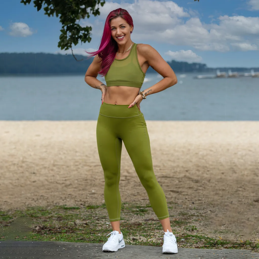 joyful woman wearing green sportswear standing near beach