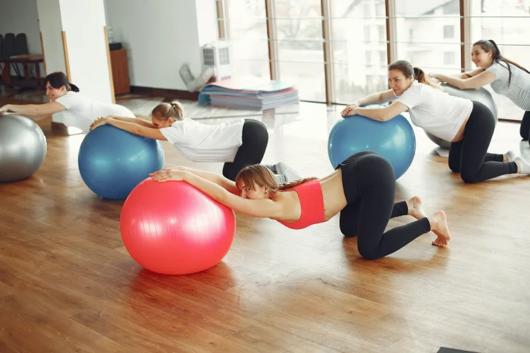 joyful women doing yoga with exercise ball