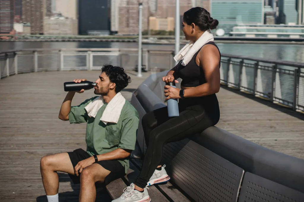 man and woman resting and drinking  water with good temperature after workout