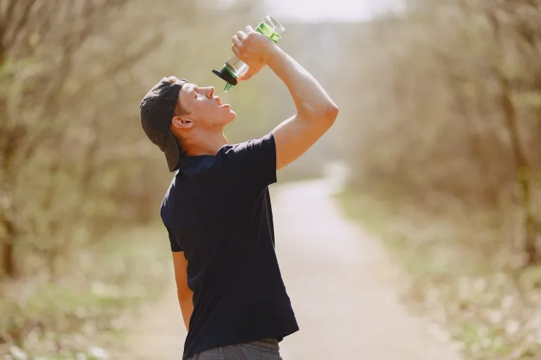 man drinking water from bottle on a lonely road