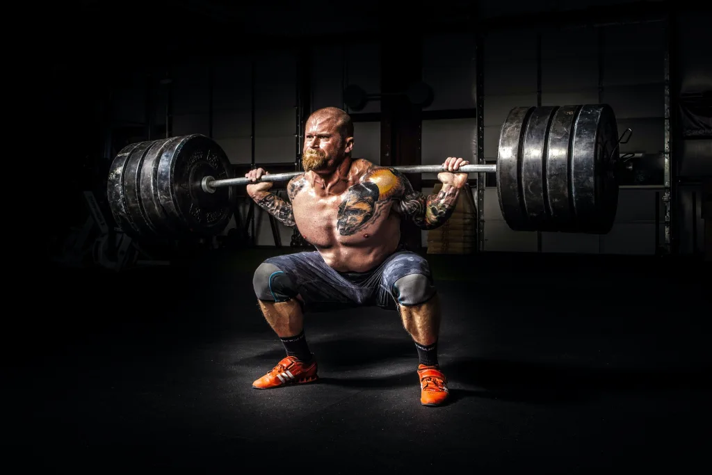 Musculine man lifting heavy barbell above his shoulder
