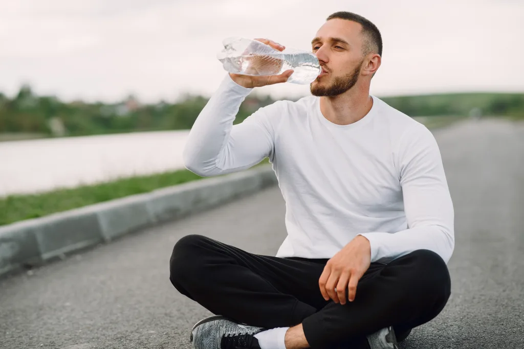 man sitting on the road drinking water for weight loss