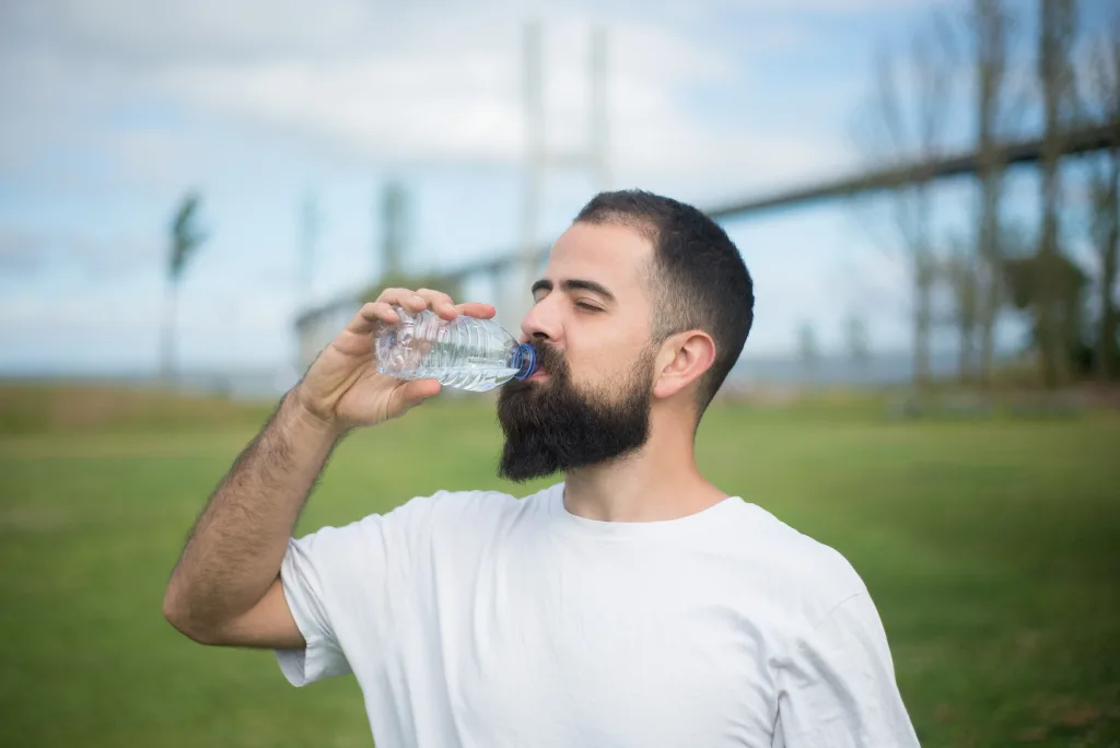 man wearing white shirt drinking water