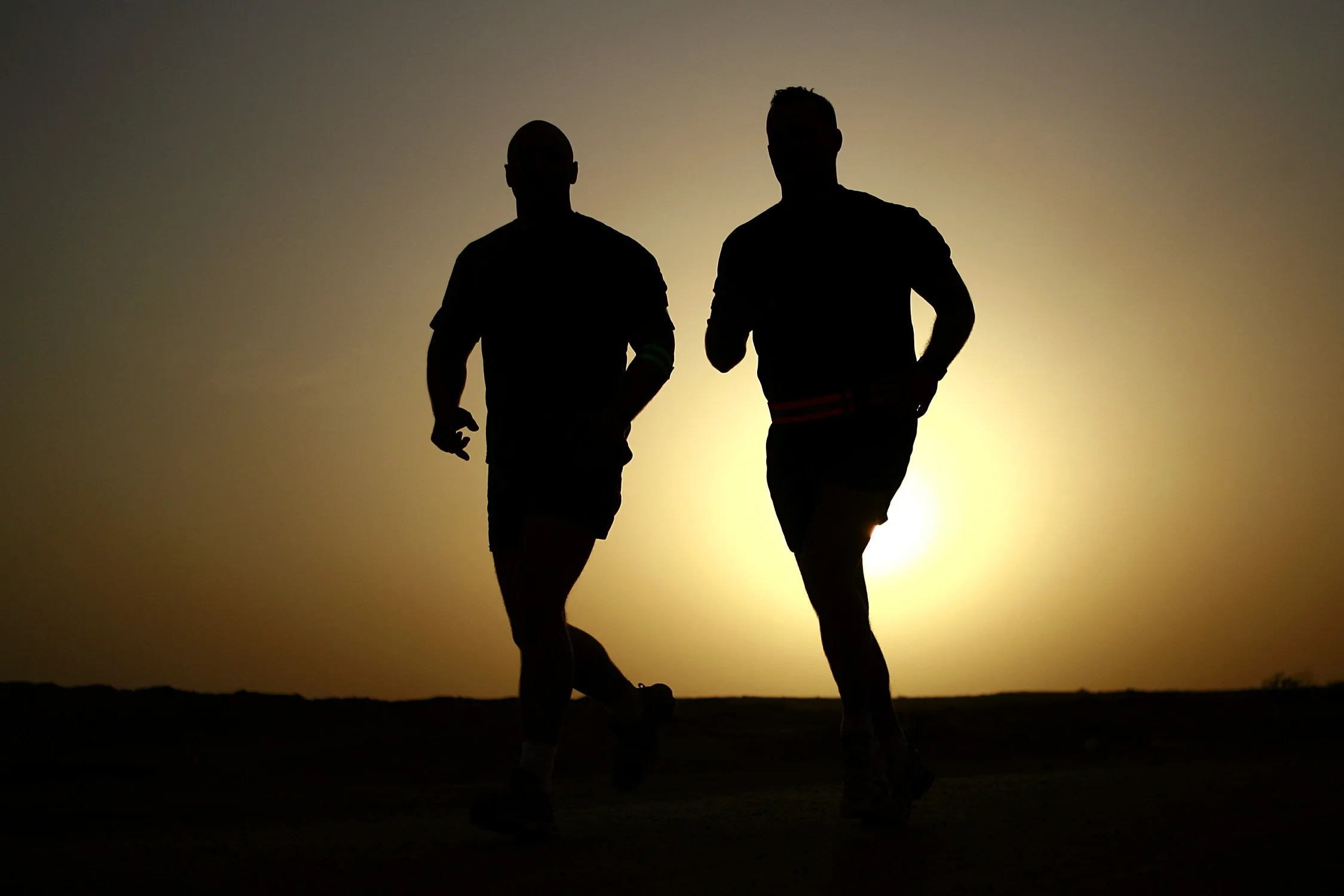 A silhouette shot of two men jogging before sunset