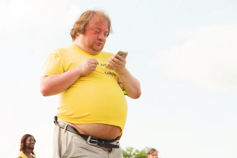 obesity overweight man in yellow shirt holding cellphone