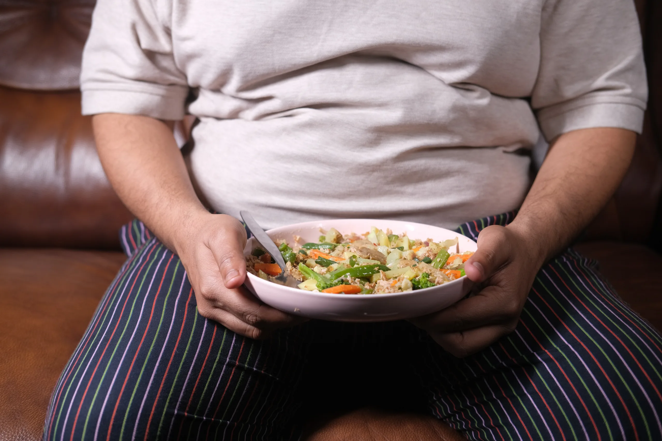 overweight person sitting holding food