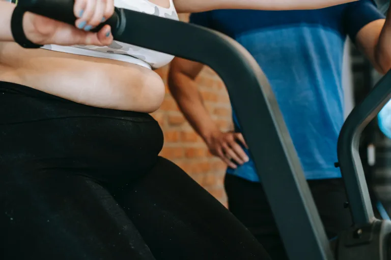 overweight obesity woman in the gym equipment beside her coach