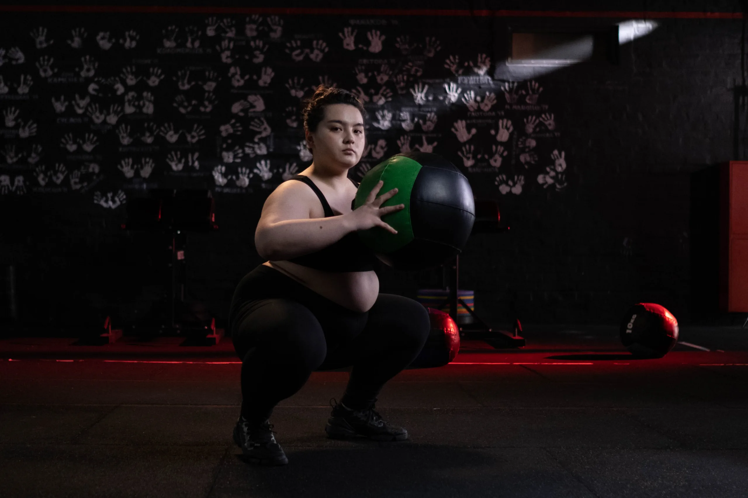 overweight woman in squat position holding ball