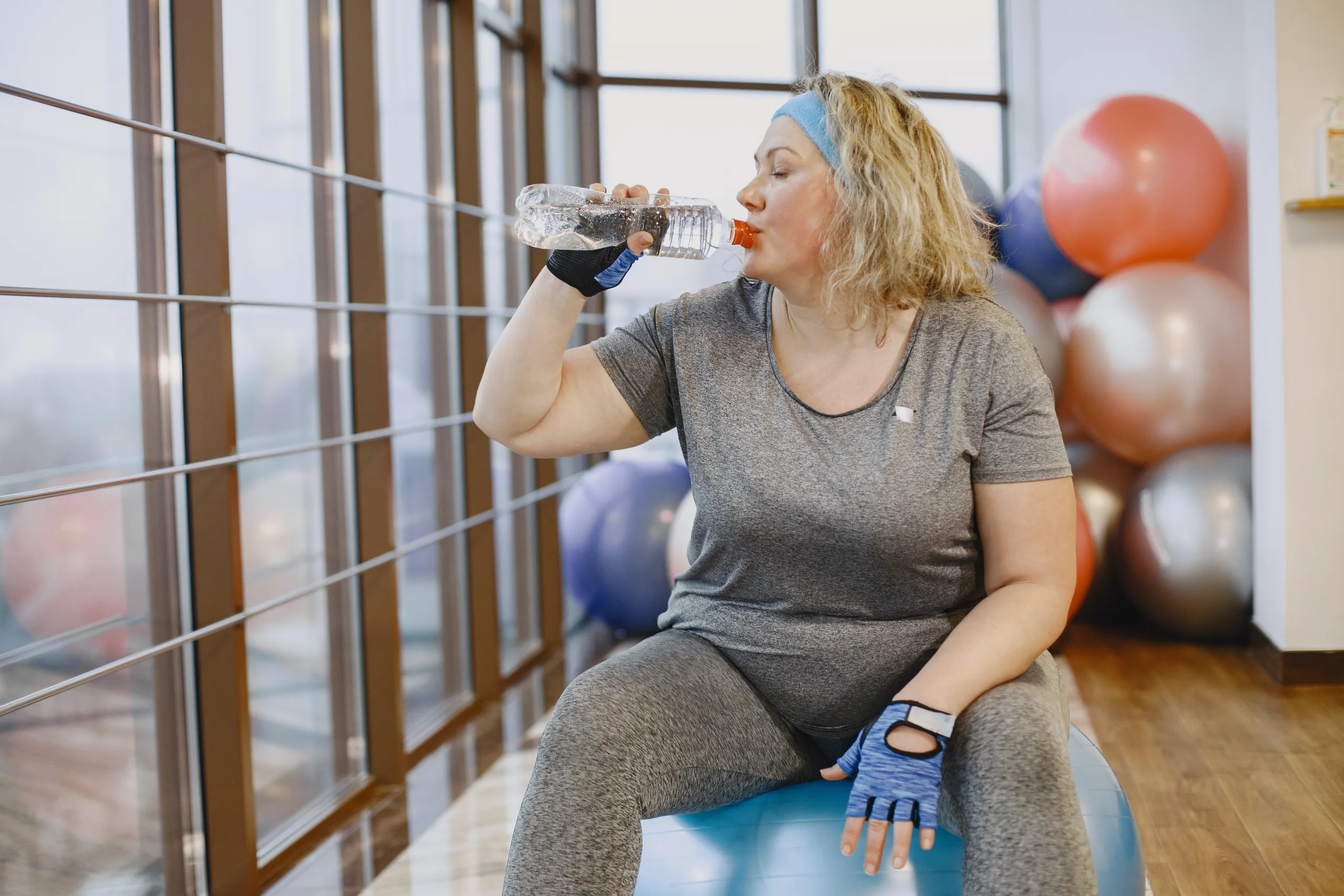 overweight woman sitting on ball drinking water