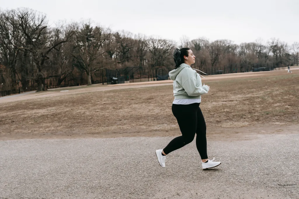 overweight woman wearing gray jacket jogging for anti-obesity