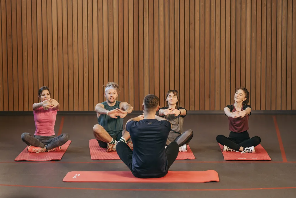 people sitting on yoga mat while stretching arms for weight loss