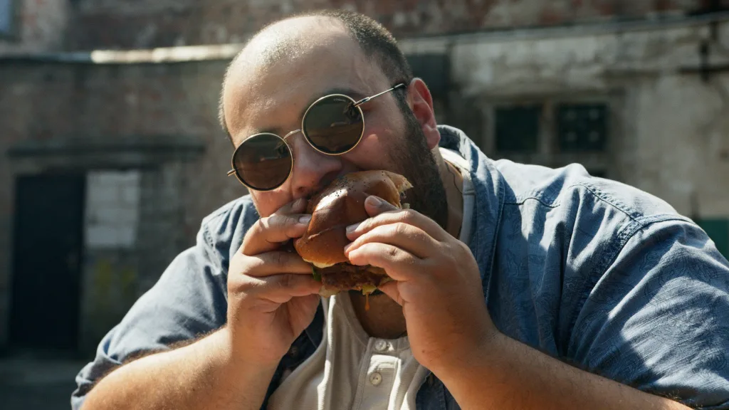 Overweight man eating burger