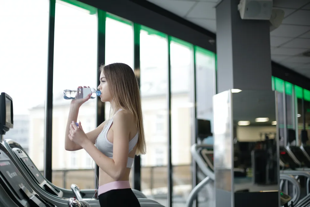 woman drinking water after exercise