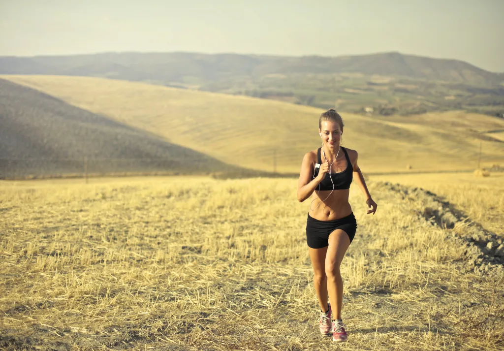 smiling woman running on dirt road while listening to music weight loss