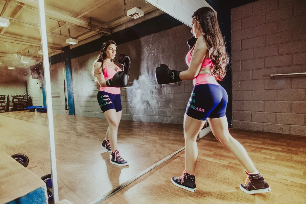 sporty woman in front of mirror practicing boxing for obesity exercise