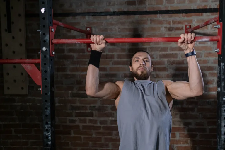 strong man hanging on steel bar kipping pull-ups