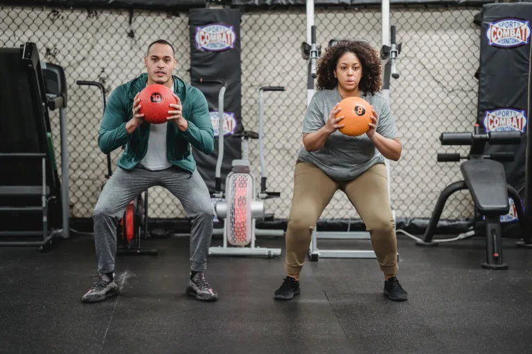 Man and woman doing work out with exercise ball hip circles tke