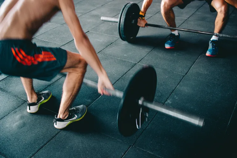 two men in the gym lifting barbell together needs a drinking water