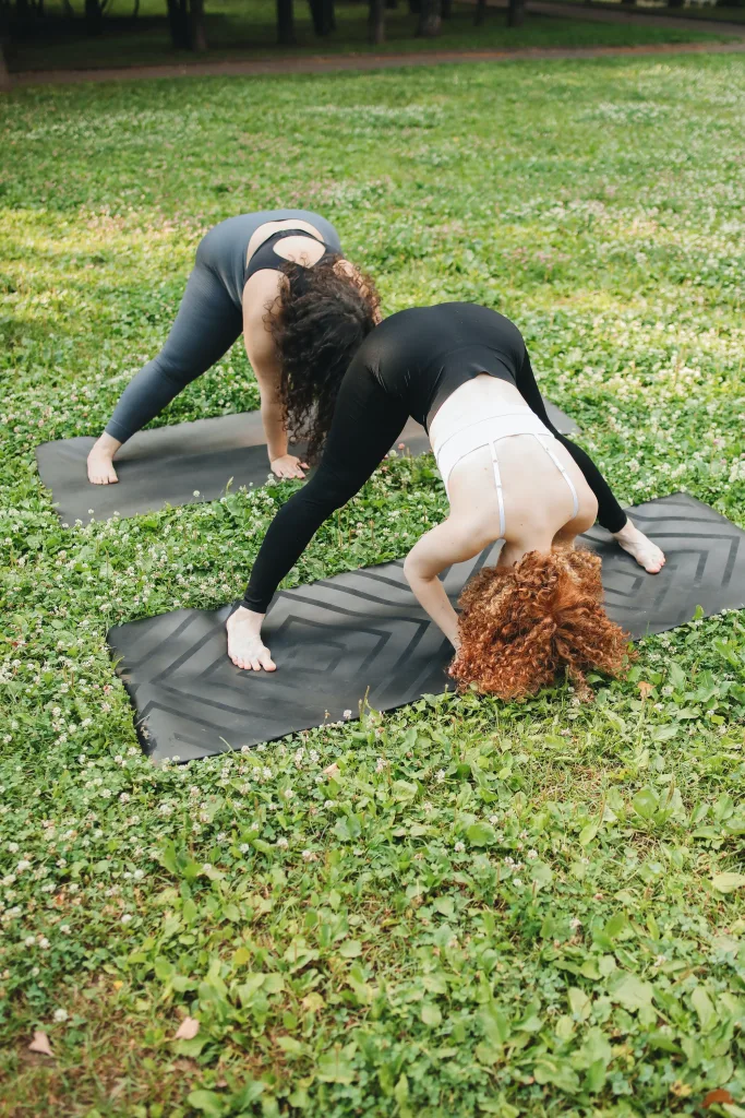 nutty-two women doing yoga on green grass