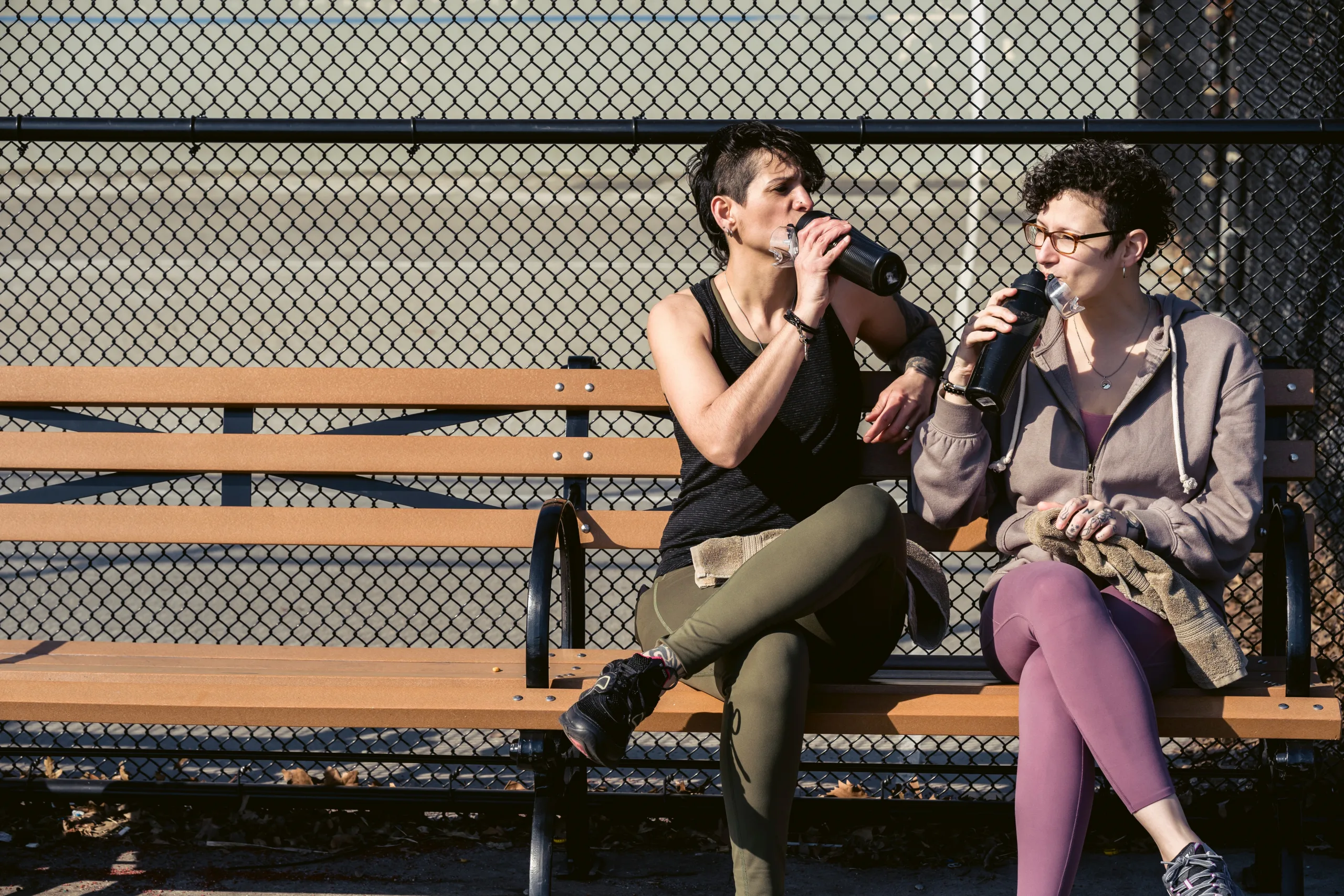 two women sitting on bench and drinking and tracking your water intake