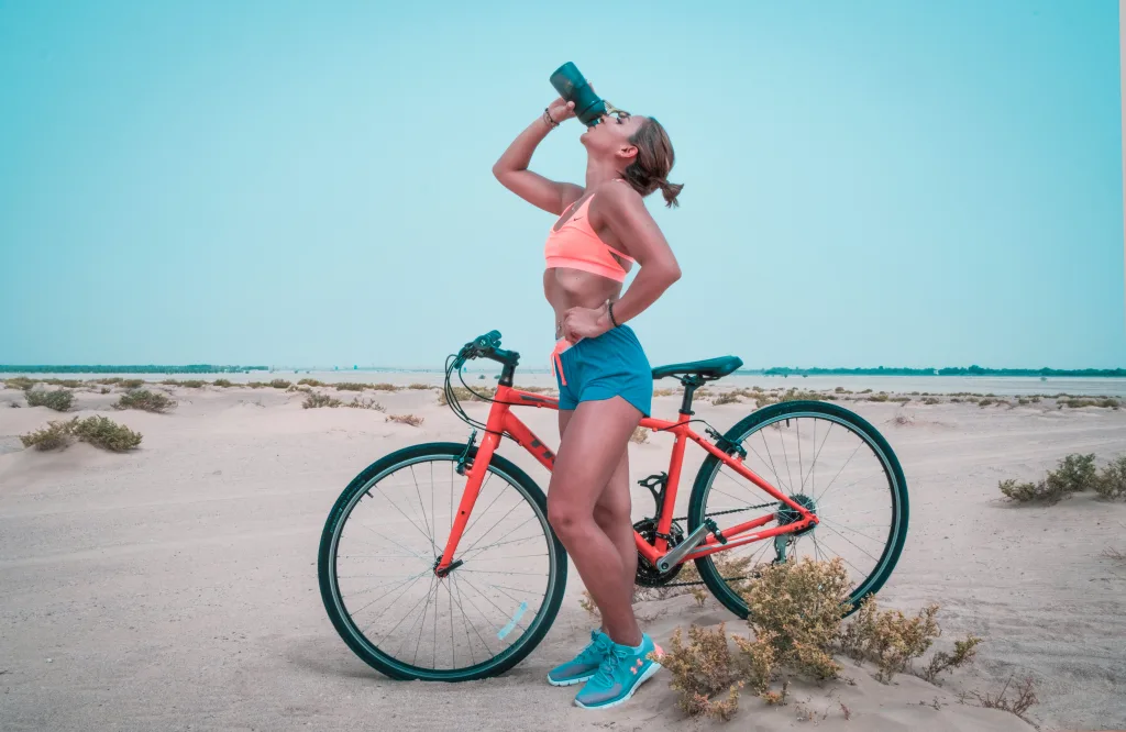 woman riding bike  for weight loss drinking water in the dessert