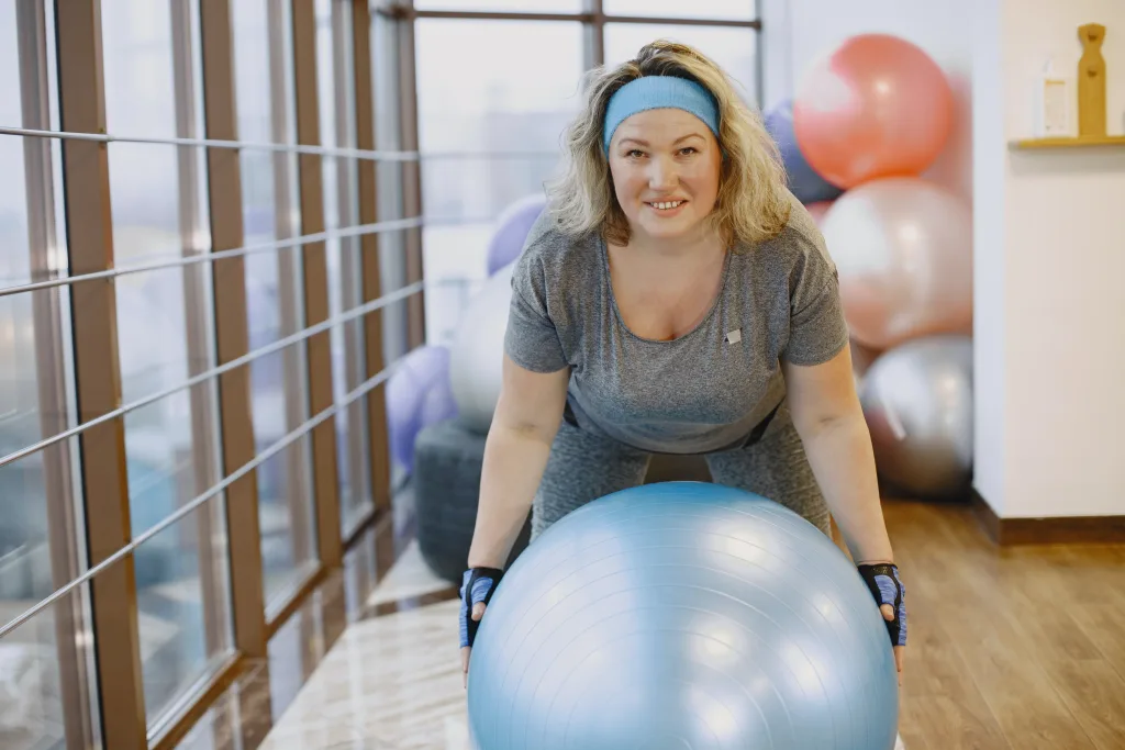 woman smiling while holding exercise ball best exercise for obese