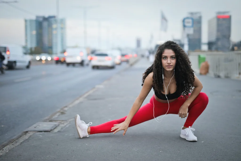 woman wearing sportswear stretching on the sidewalk