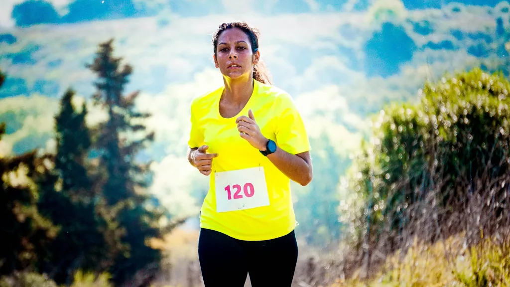 Tired woman wearing yellow shirt is focus to finish the marathon