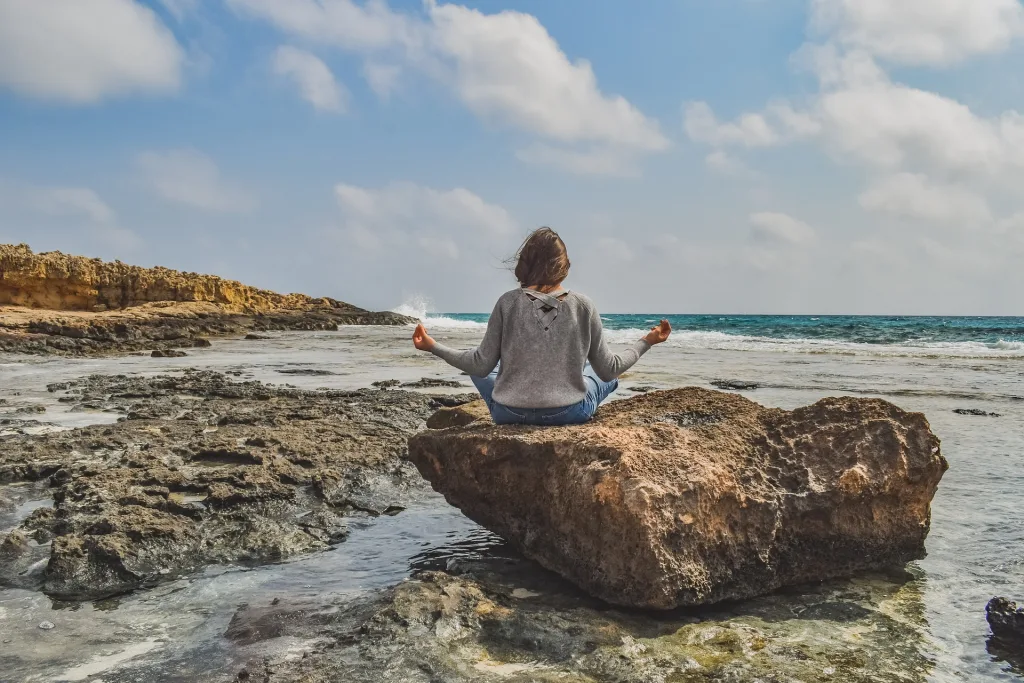 Calm woman meditating on top of rock