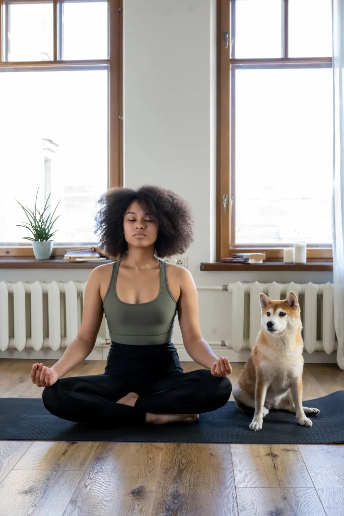 Calm woman meditating at home beside her dog