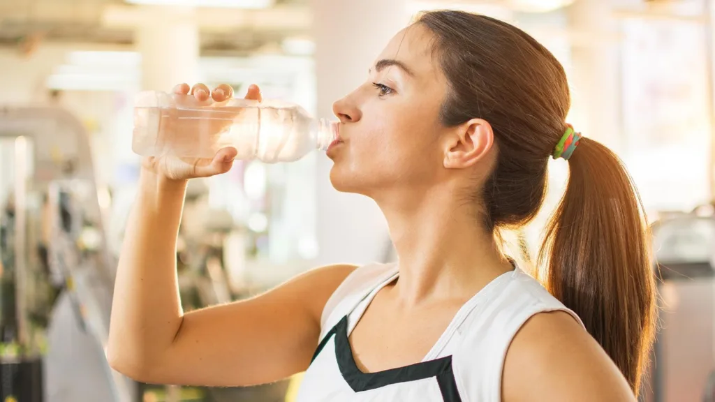 woman after workout drinking more water