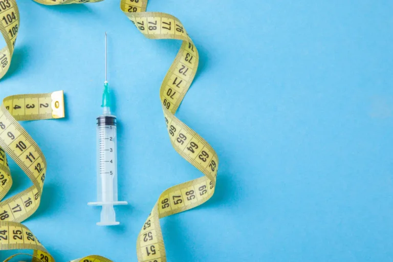 hcg injections and tape measure on a blue background