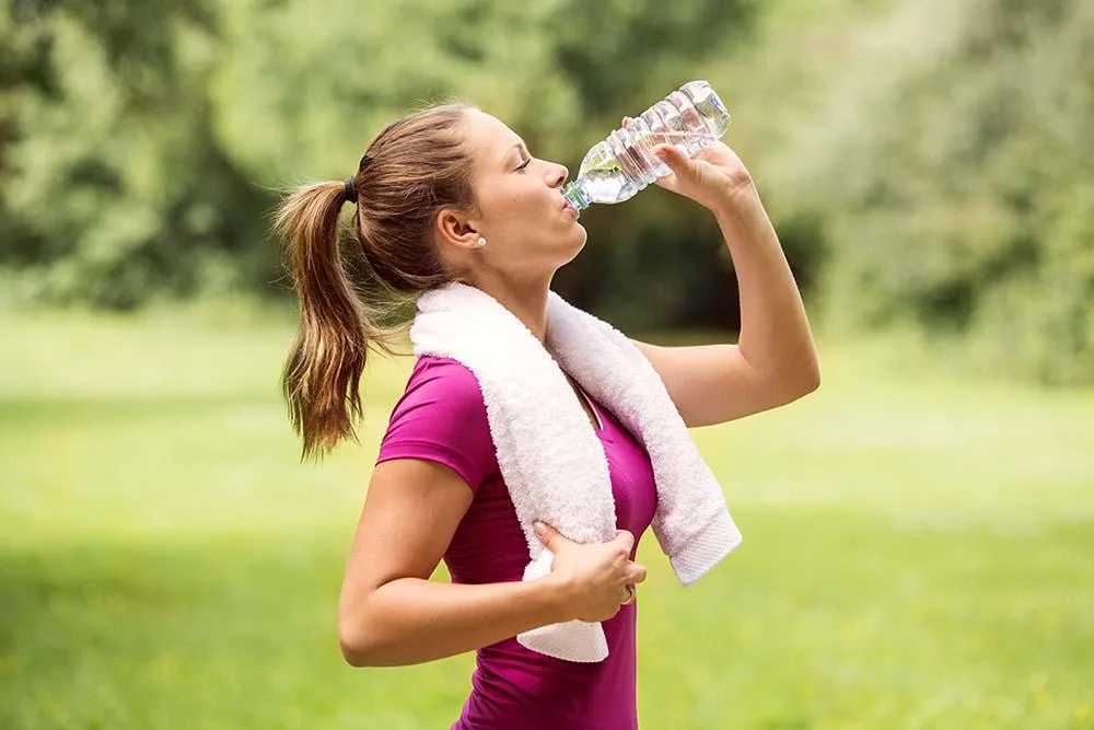 woman with towel drinking more water Hydration