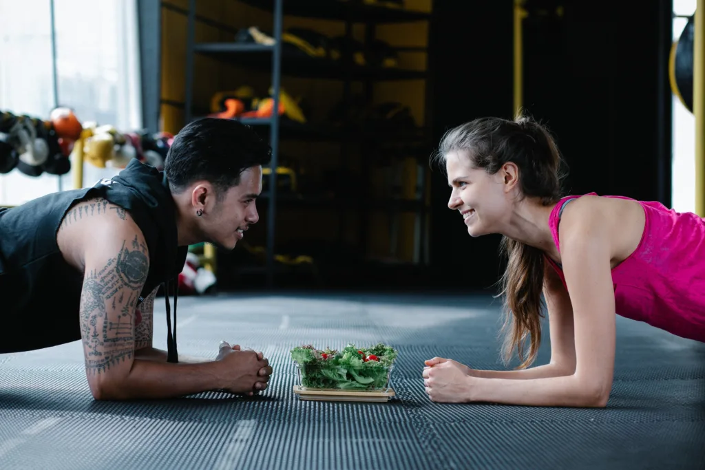vegetarian man and woman with vegetable meal while planking